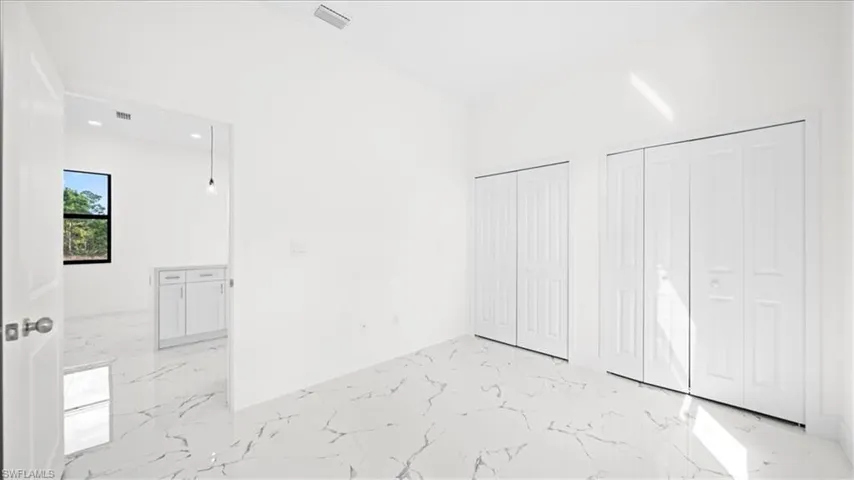 Unfurnished bedroom featuring light marble finish flooring, multiple closets, and recessed lighting
