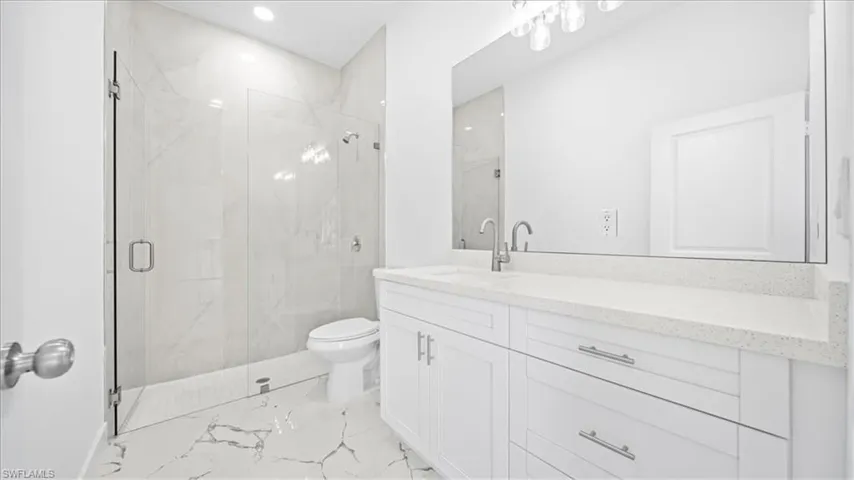 Full bath featuring a marble finish shower, vanity, recessed lighting, and light marble finish floors