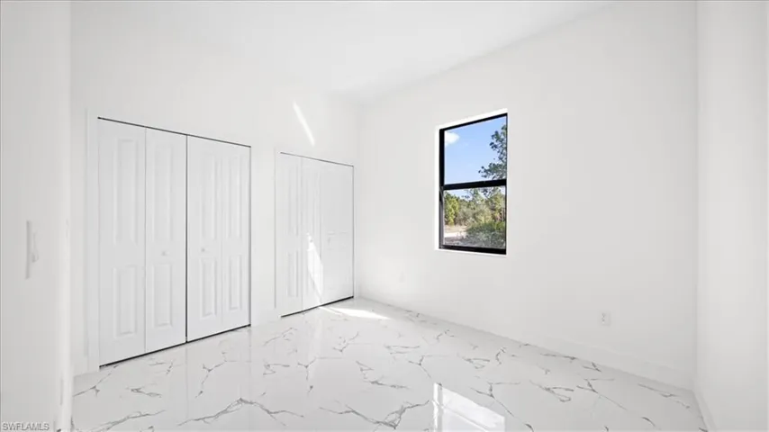 Unfurnished bedroom featuring multiple closets and light marble finish flooring