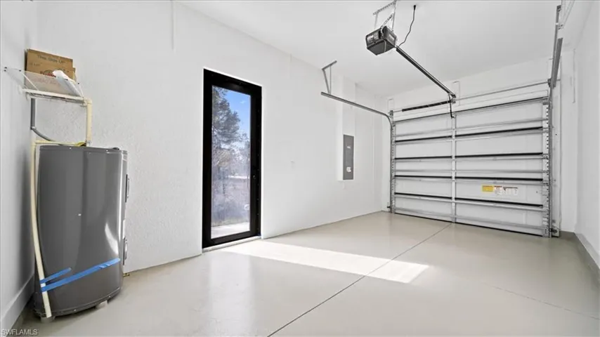 Garage featuring water heater, electric panel, and a garage door opener
