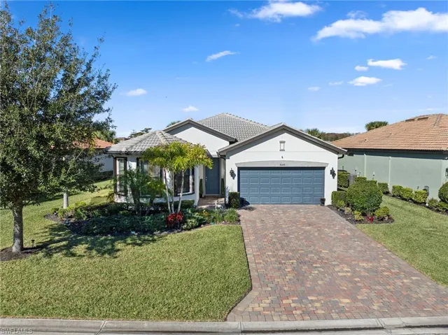 Single story home featuring a front yard, stucco siding, decorative driveway, and a garage