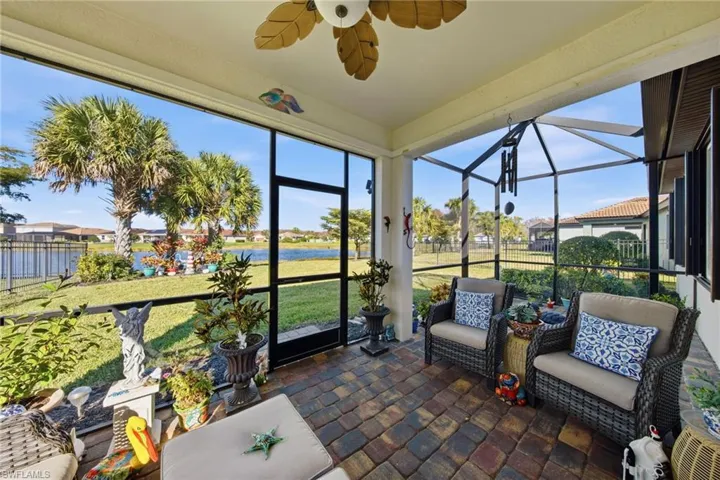 Sunroom with ceiling fan, a water view, a residential view, and a patio