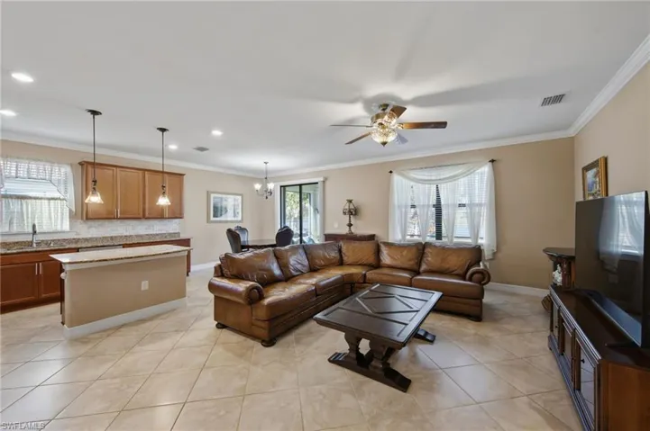 Living area with ceiling fan, ornamental molding, a chandelier, and light tile patterned floors