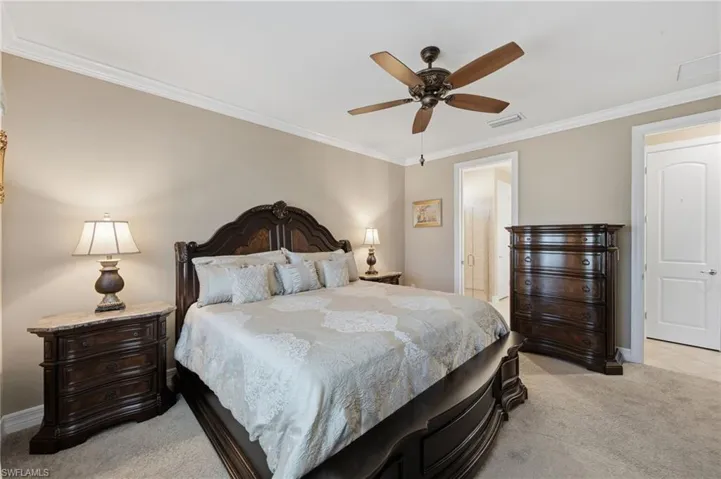 Bedroom with crown molding, light colored carpet, and a ceiling fan