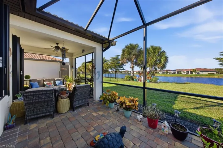 View of patio featuring a sunroom, glass enclosure, ceiling fan, and a water view