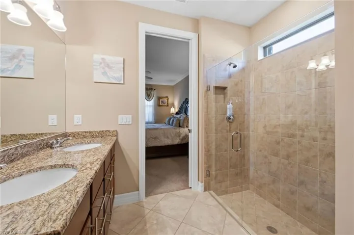 Bathroom with ornamental molding, ensuite bath, double vanity, a shower stall, and light tile patterned floors