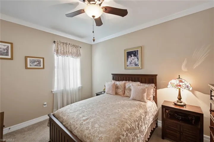 Bedroom featuring ornamental molding, light carpet, and a ceiling fan