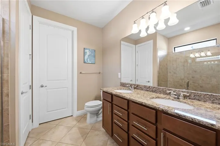 Bathroom with a shower stall, double vanity, and light tile patterned floors