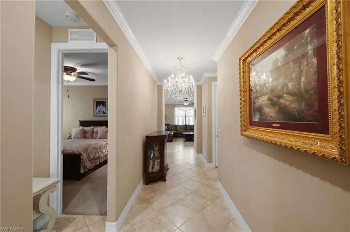 Hall with ornamental molding, suspended lighting, and light tile patterned floors