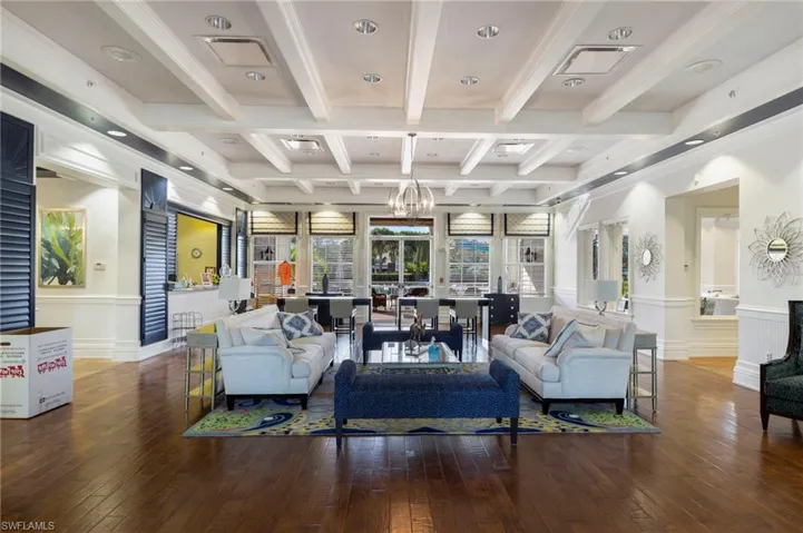 Living area with hanging lights, beamed ceiling, hardwood / wood-style flooring, a wainscoted wall, and ornamental molding