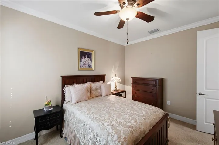 Bedroom featuring crown molding, light carpet, and a ceiling fan