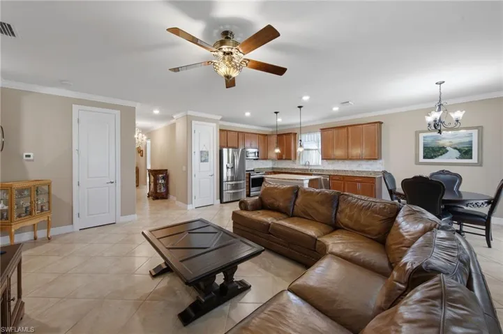 Living area with hanging lights, crown molding, a ceiling fan, and light tile patterned floors