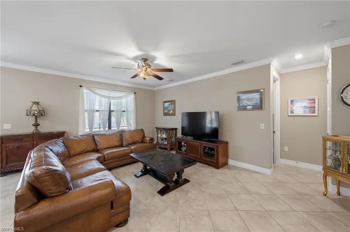 Living area with ornamental molding, ceiling fan, and light tile patterned flooring