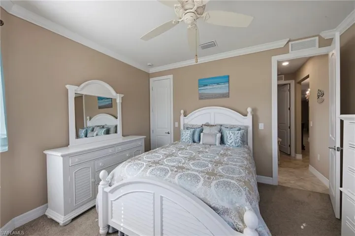 Bedroom featuring light colored carpet, ornamental molding, and a ceiling fan