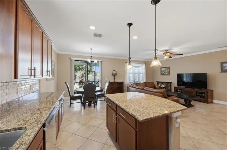 Kitchen featuring light stone counters, open floor plan, light tile patterned flooring, a kitchen island, and stainless steel dishwasher