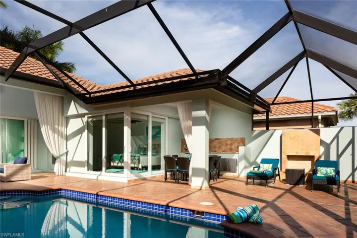 Rear view of property with glass enclosure, a sunroom, a tiled roof, stucco siding, and a patio area