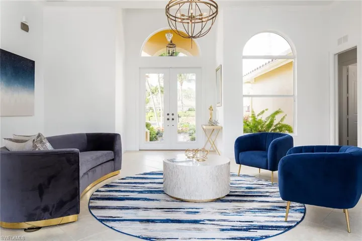 Sitting room featuring french doors, tile patterned flooring, ornamental molding, a high ceiling, and a chandelier