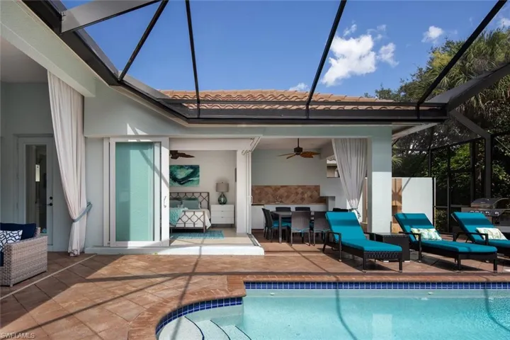 Swimming pool featuring glass enclosure, a sunroom, a patio, and area for grilling