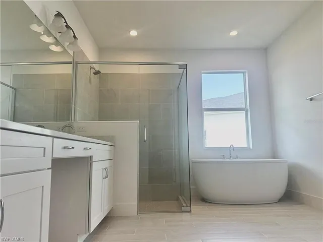 Primary bathroom with luxe walk-in shower, beautiful shower floor and wall tile, free-standing Kohler tub, and private water closet