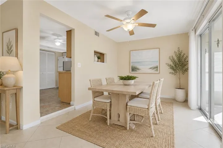 Dining area featuring tile flooring, a ceiling fan with integrated lighting, and a sliding glass door providing natural light