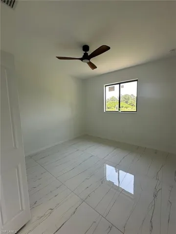 Tiled spare room featuring ceiling fan