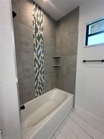 Bathroom with tiled shower / bath and tile patterned flooring