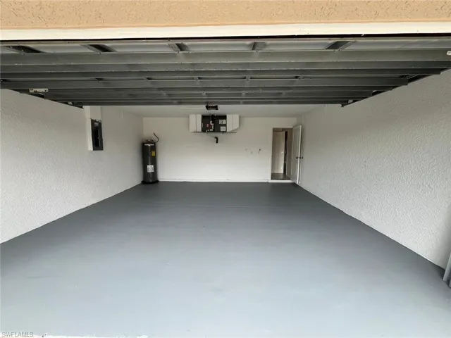 Garage with a textured wall, water heater, and electric panel