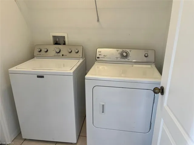 Laundry area with washer and dryer and light tile patterned flooring