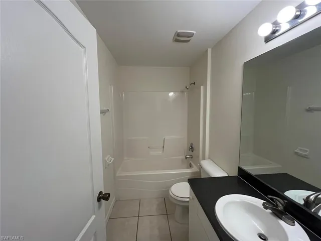 Bathroom with vanity, bathing tub / shower combination, and light tile patterned floors