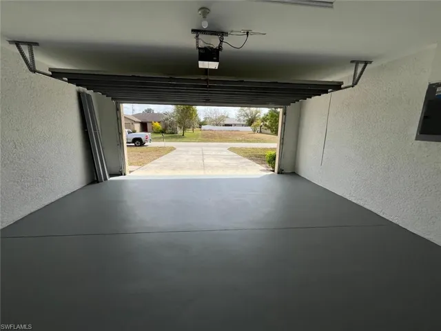 Garage featuring a textured wall, electric panel, and a garage door opener