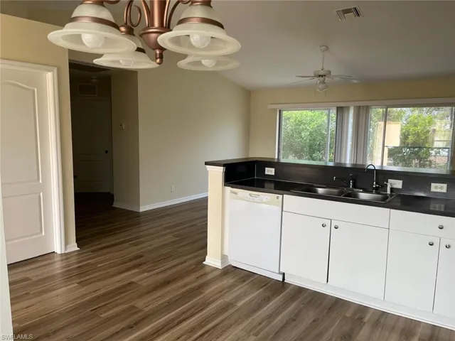 Kitchen featuring dark countertops, white dishwasher, white cabinetry, a ceiling fan, and dark wood-style flooring
