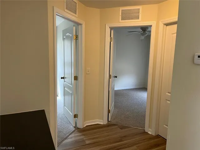 Corridor featuring dark wood-style flooring and dark carpet