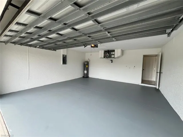 Garage featuring a textured wall, electric water heater, and electric panel