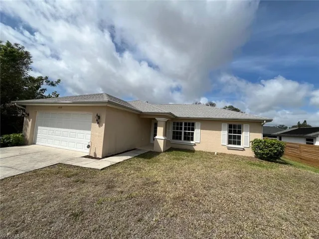 Single story home with stucco siding, an attached garage, concrete driveway, and a front yard