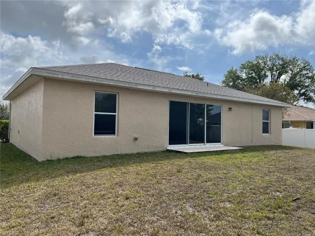 Back of property with stucco siding and a shingled roof