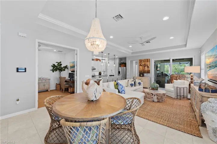 Dining room with view of the lanai through the IMPACT GLASS SLIDING GLASS DOORS. New CUSTOM CHANDELIER (November 2021), new THERMOSTAT (August 2021)