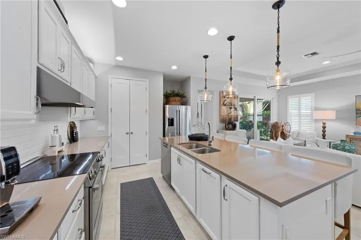 Entertaining kitchen features neutral finishes, TILE BACKSPLASH, QUARTZ counters and ROLL-OUT TRASH drawer.
