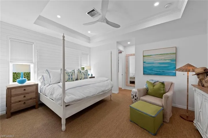 Retreat to the large primary suite with an abundance of CUSTOM UPGRADES. New SHIPLAP WALL (May 2024), new ADDED CAN LIGHTS (September 2023), new SISAL CARPET (February 2022), new CEILING FAN (January 2022), new TV MOUNT & RAISED OUTLET (November 2021), new AUTOMATED WINDOW BLINDS (August 2021)