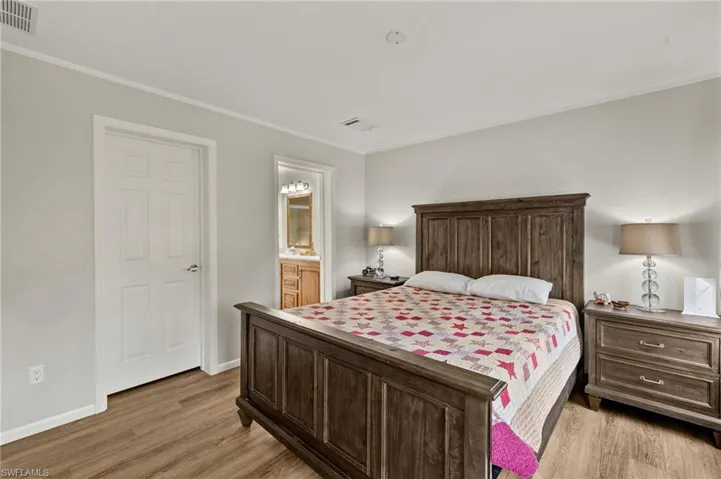 Bedroom with light hardwood / wood-style flooring, ensuite bath, and ornamental molding