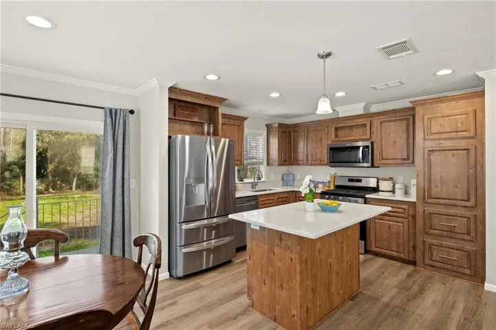 Kitchen with a center island, decorative light fixtures, sink, ornamental molding, and appliances with stainless steel finishes