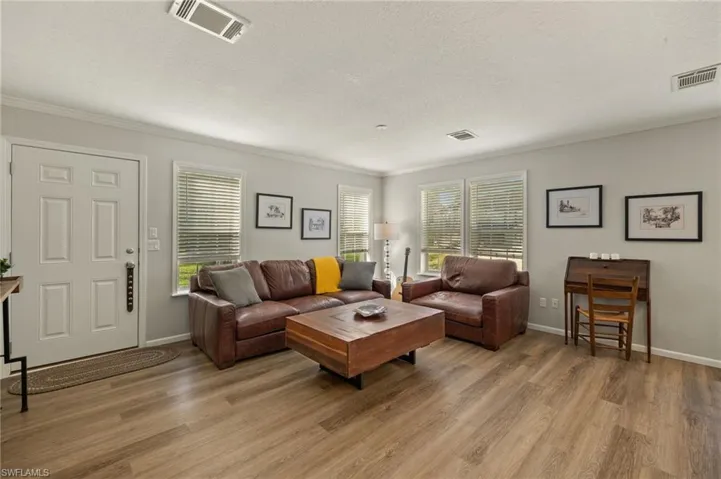 Living room with light hardwood / wood-style flooring, a textured ceiling, and a healthy amount of sunlight