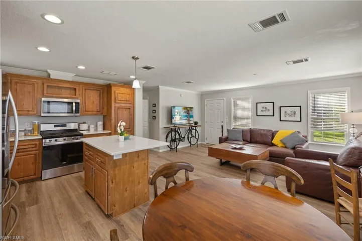 Kitchen with light wood-type flooring, stainless steel appliances, pendant lighting, and a center island