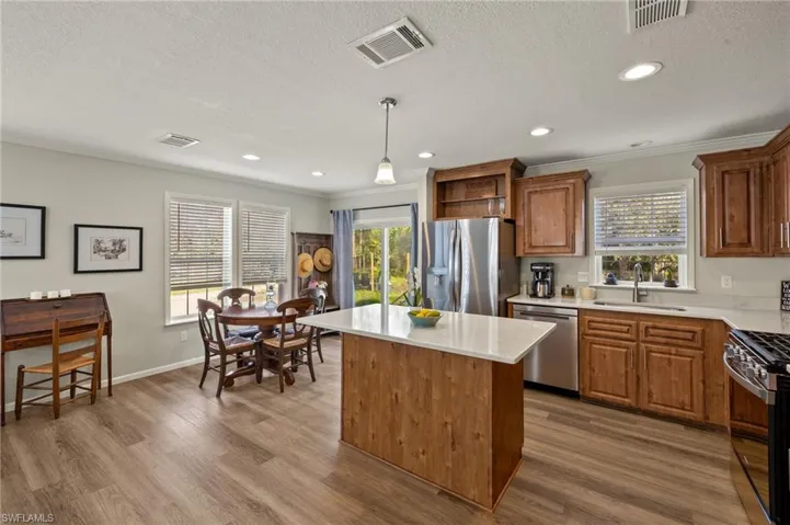 Kitchen featuring hardwood / wood-style flooring, stainless steel appliances, a center island, decorative light fixtures, and sink