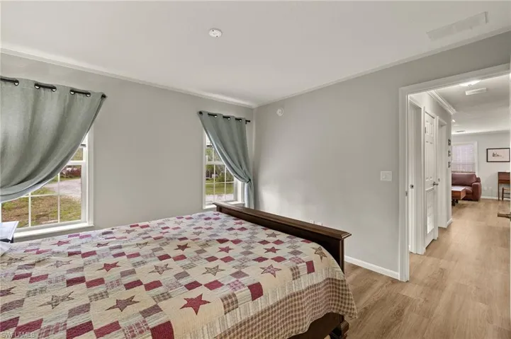 Bedroom with multiple windows, ornamental molding, and light hardwood / wood-style flooring