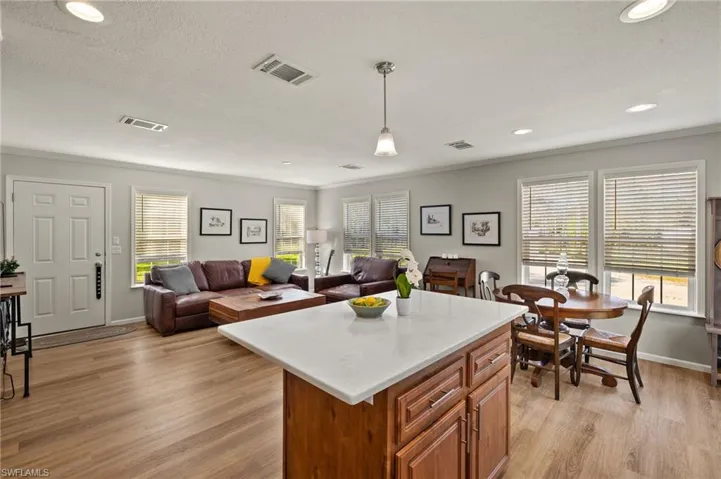 Kitchen featuring light hardwood / wood-style flooring, hanging light fixtures, a textured ceiling, crown molding, and a kitchen island