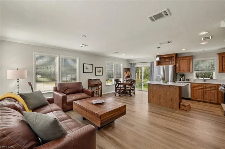 Living room featuring ornamental molding, sink, light hardwood / wood-style floors, and a textured ceiling