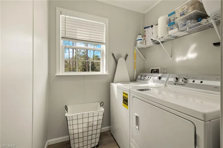 Laundry area featuring washer and dryer, dark wood-type flooring, and crown molding