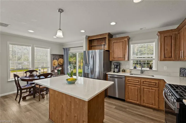 Kitchen with wood-type flooring, sink, a center island, pendant lighting, and stainless steel appliances