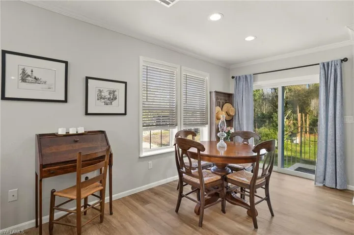 Dining space with crown molding and light hardwood / wood-style flooring