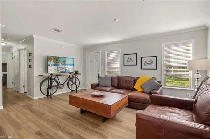 Living room with light wood-type flooring and crown molding
